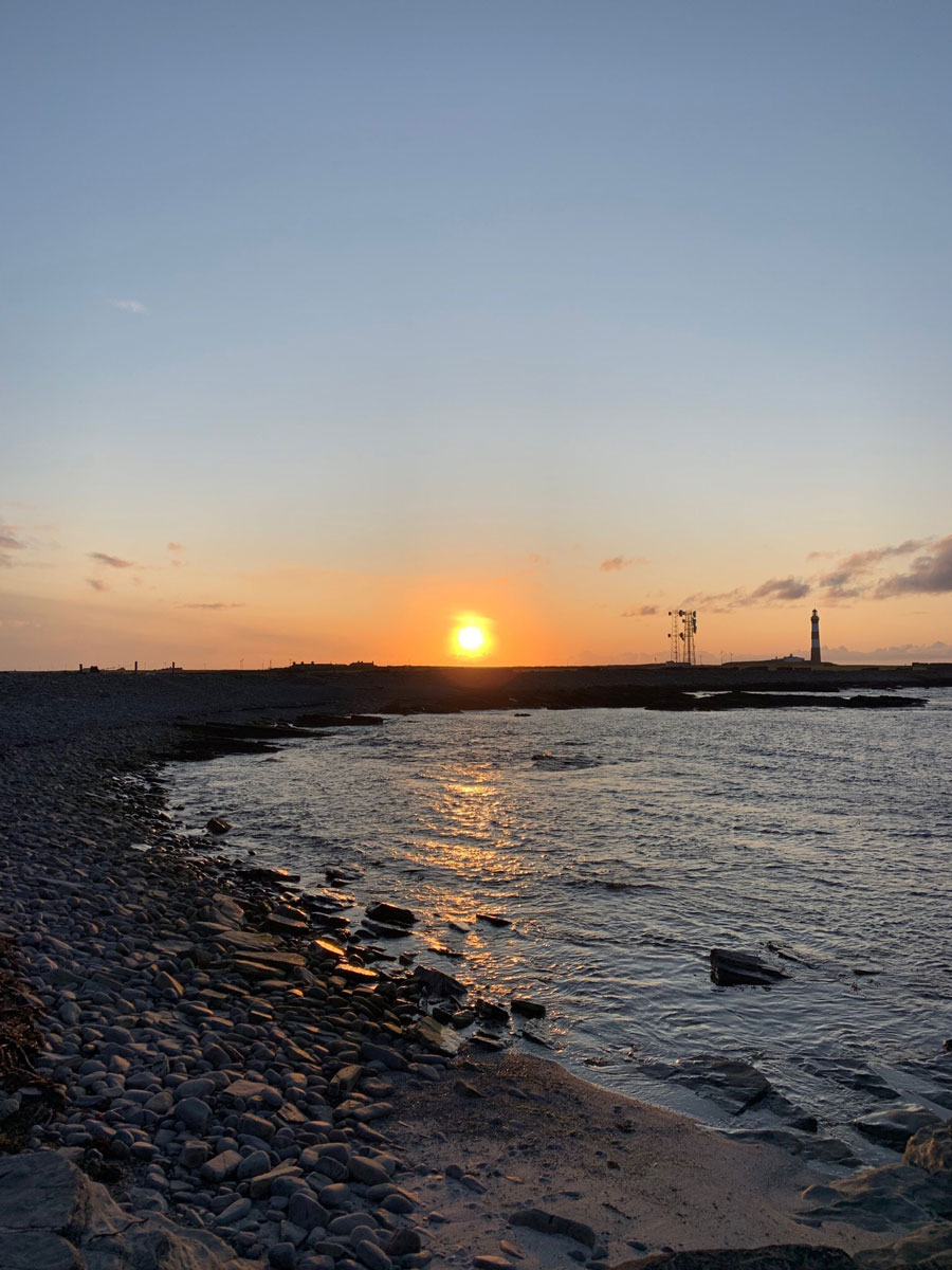 North Ronaldsay beach with lighhouse and sunset